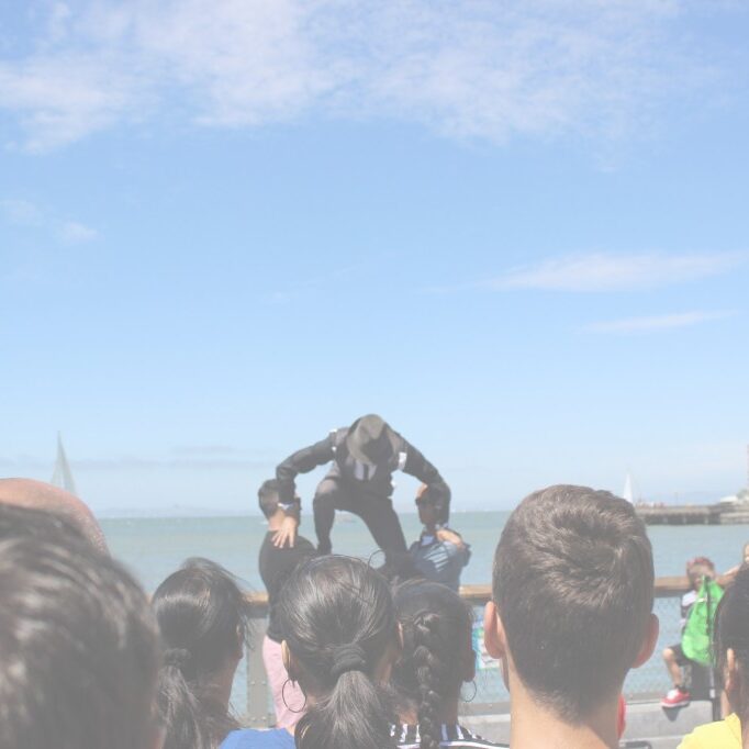 bookingbglight standing on 2 guys-1024x682